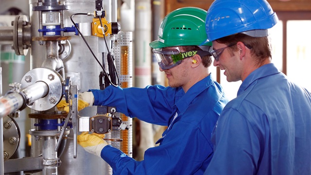 Junge Chemikanten überwachen Produktionsanlage in Chemiefabrik.