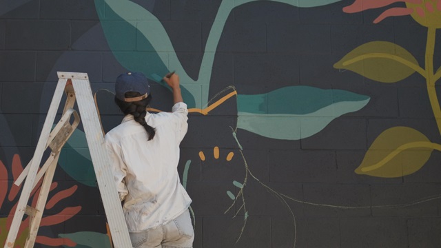 Frau malt Mural, dessen Farben auf Spezialchemikalien basieren.